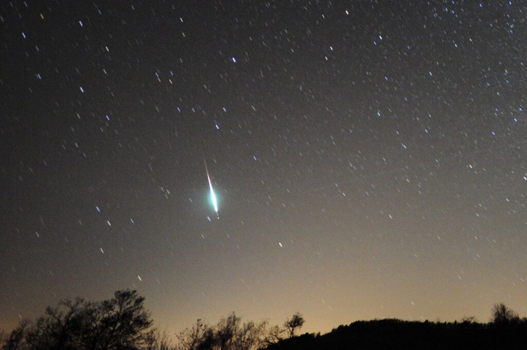 The photo shows a big -10 magnitude green Taurid fireball low in the western sky, just above the horizon.